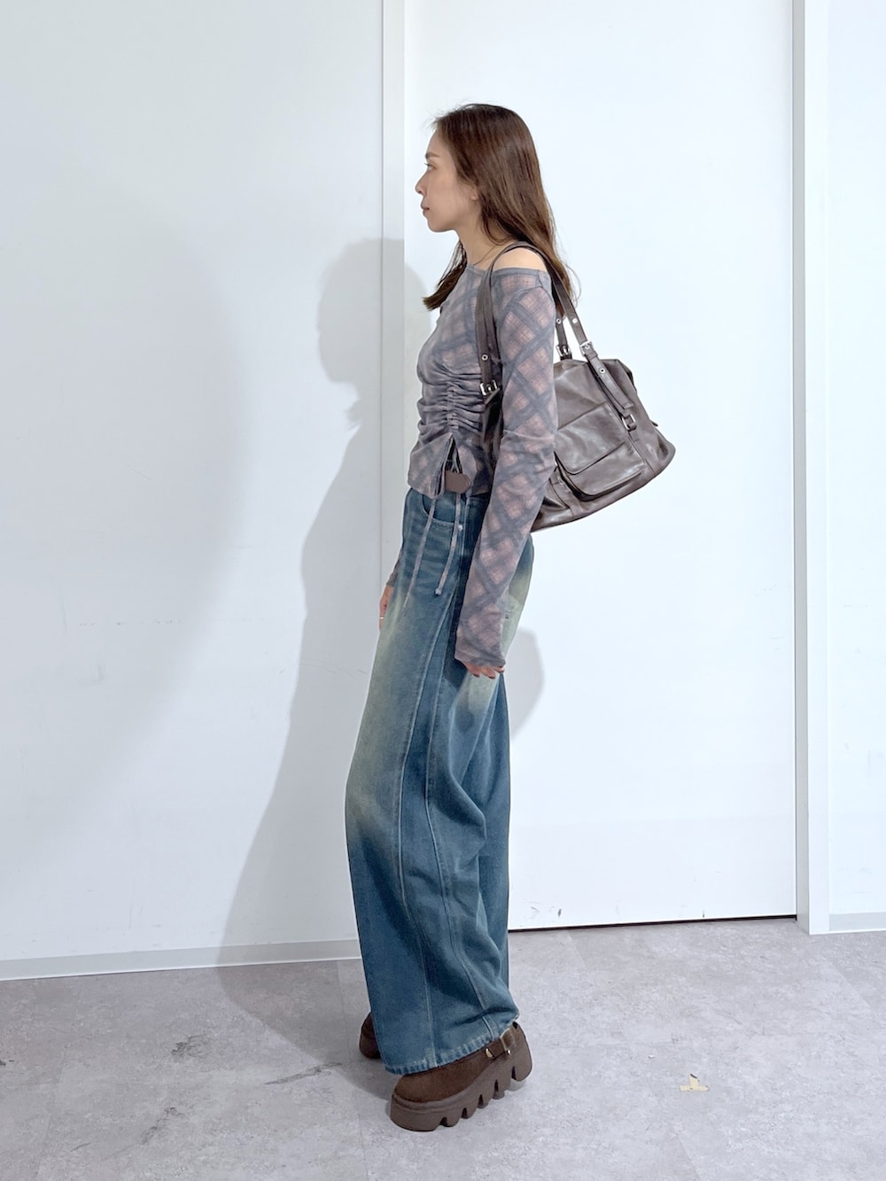 ブラウン系のショルダーバッグ、ブラウン系のTシャツ/カットソー、ブルー系のデニムパンツを着用したレディースの夏コーディネートの4枚目の写真