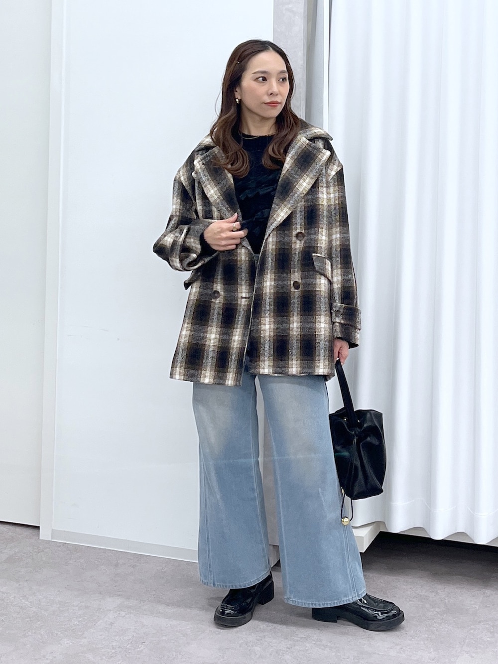 ブラック系のショルダーバッグ、ブルー系のデニムパンツ、ブラック系のニット/セーターを着用したレディースの冬コーディネートの2枚目の写真