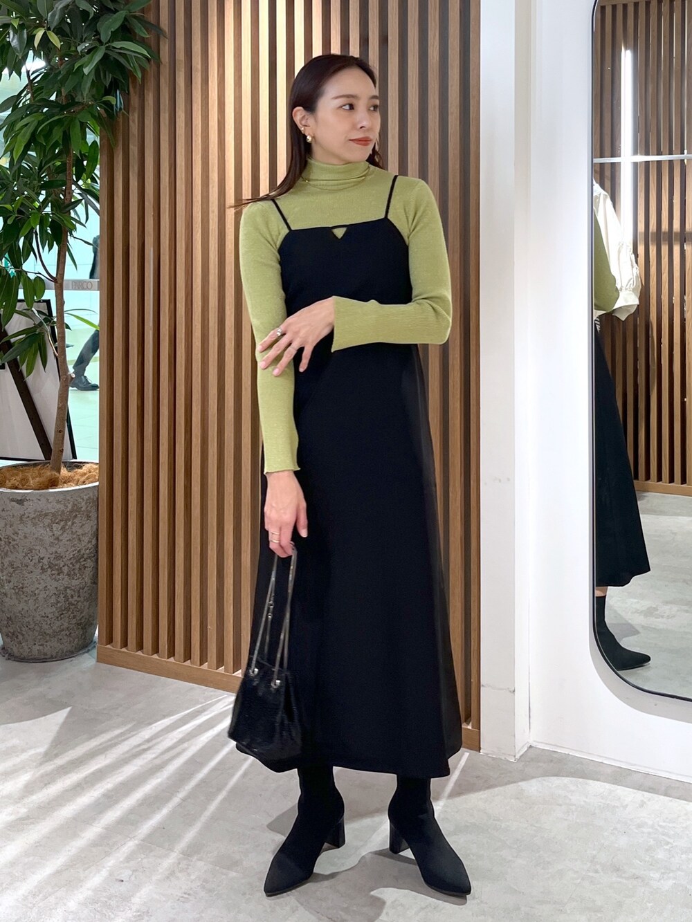 ブラック系のショルダーバッグ、ブラック系のワンピース、グリーン系のニット/セーターを着用したレディースの冬コーディネートの4枚目の写真