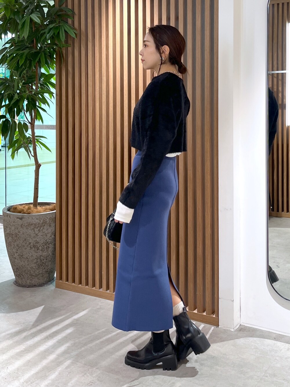 ブラック系のカーディガン/ボレロ、ブラック系のショルダーバッグ、ブルー系のスカートを着用したレディースの冬コーディネートの10枚目の写真