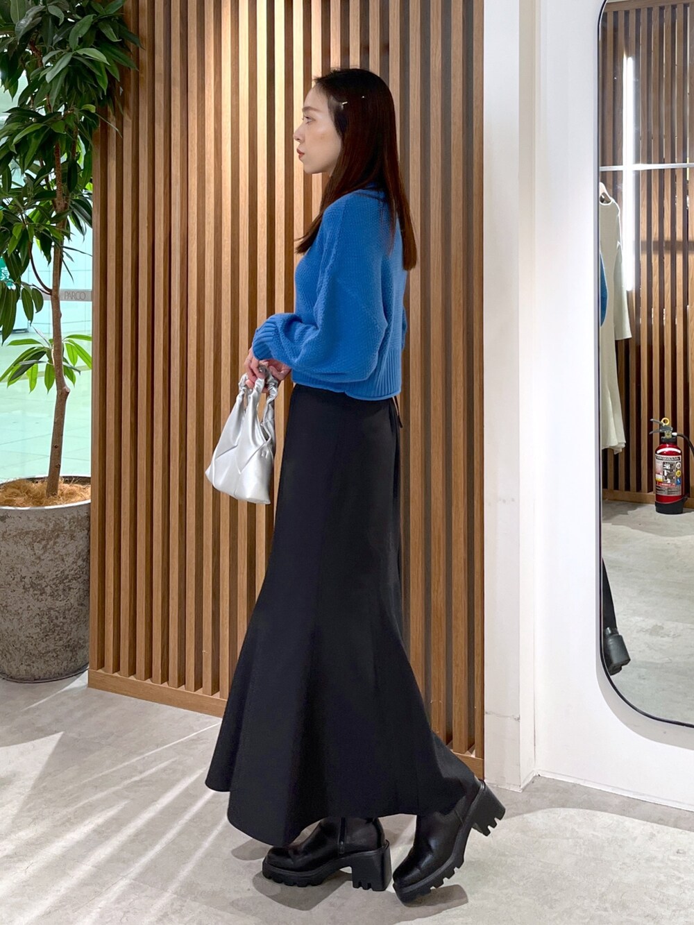 シルバー系のショルダーバッグ、ブラック系のスカート、ブルー系のニット/セーターを着用したレディースの秋コーディネートの2枚目の写真