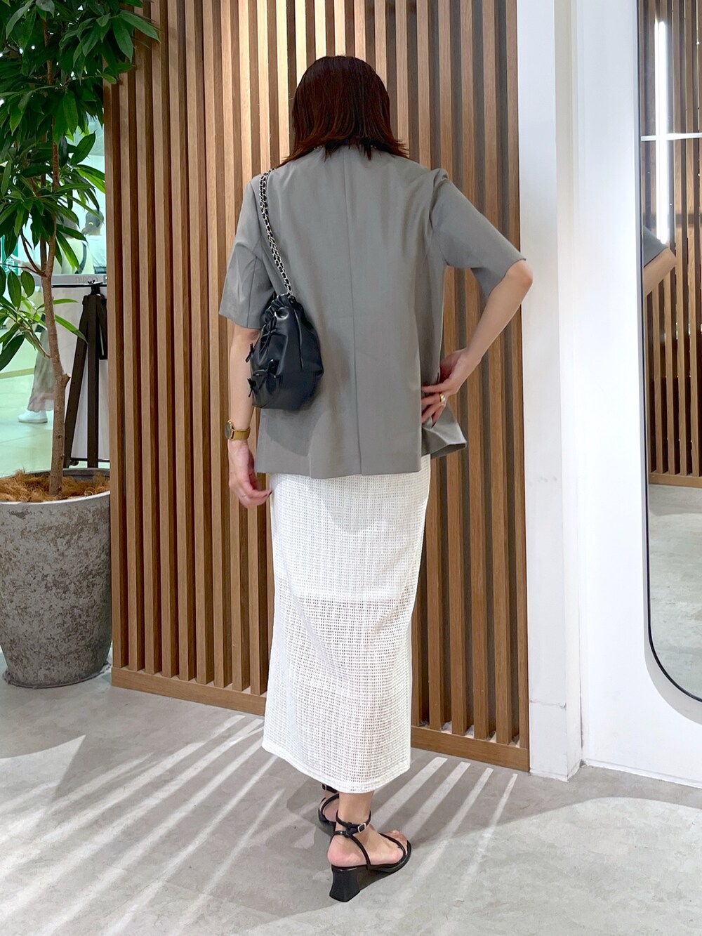 グレー系のノーカラージャケット、ブラック系のショルダーバッグ、ホワイト系のタンクトップを着用したレディースの夏コーディネートの6枚目の写真