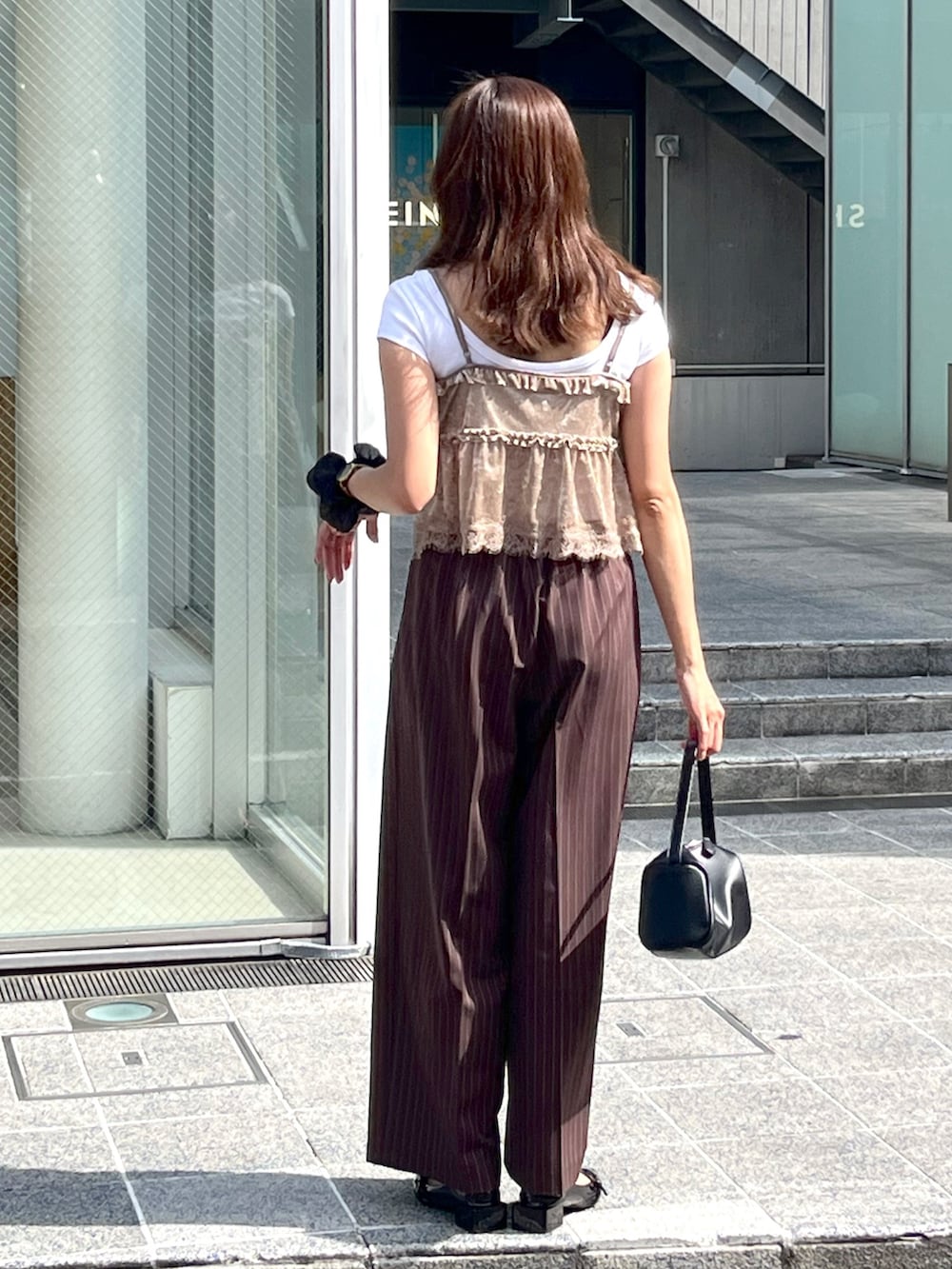 ブラック系のハンドバッグ、ブラック系のパンプス、ホワイト系のTシャツ/カットソーを着用したレディースの夏コーディネートの8枚目の写真
