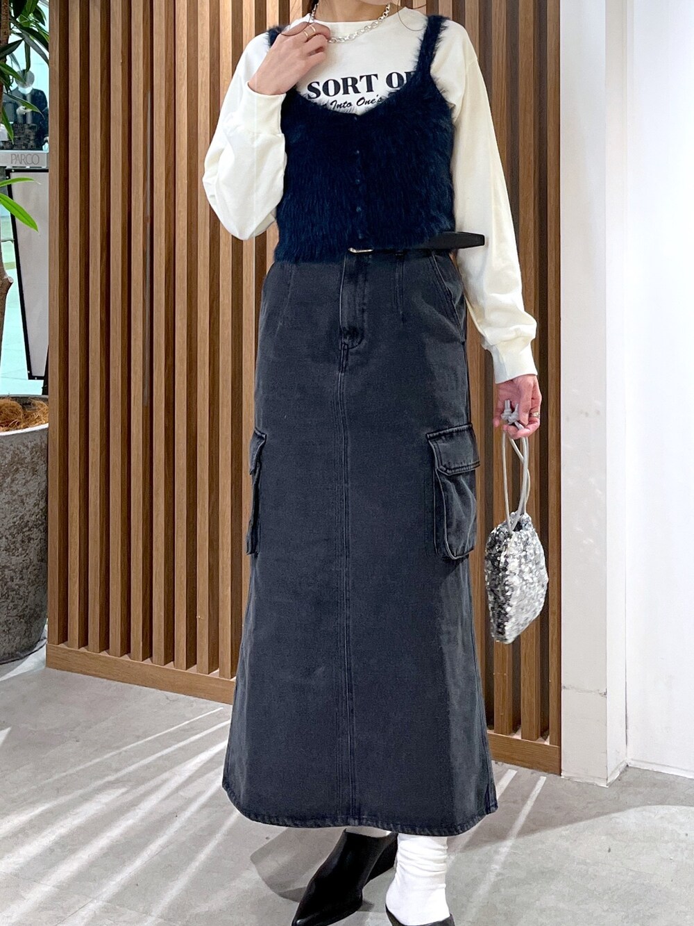 ベージュ系のTシャツ/カットソー、ブルー系のベスト、シルバー系のハンドバッグを着用したレディースの冬コーディネートの7枚目の写真