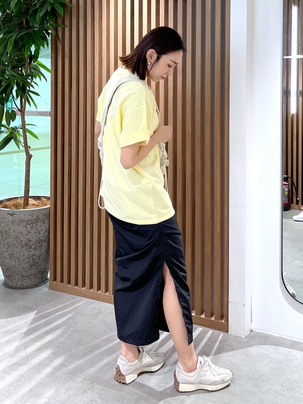 イエロー系のTシャツ/カットソー、ホワイト系のショルダーバッグ、ブラック系のスカートを着用したレディースの春コーディネートの5枚目の写真