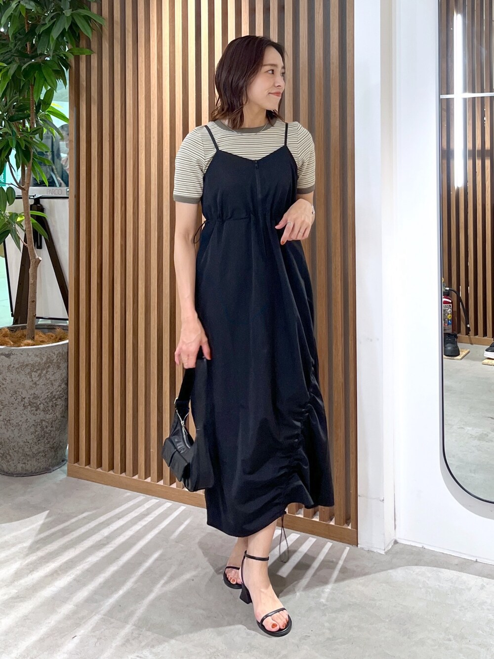 グリーン系のTシャツ/カットソー、ブラック系のショルダーバッグ、ブラック系のサンダルを着用したレディースの春コーディネートの4枚目の写真