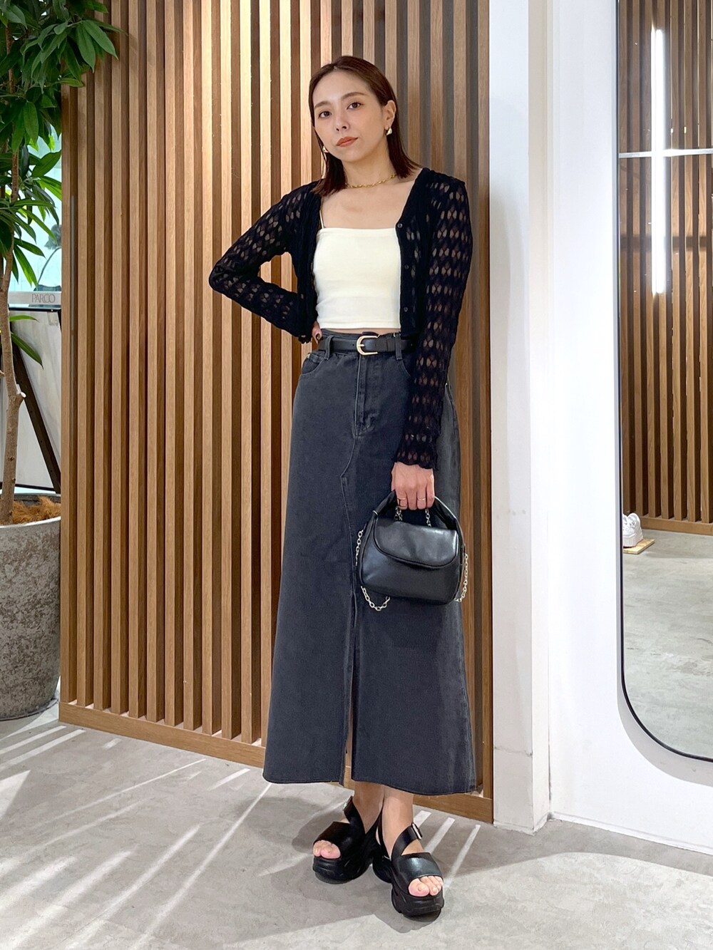 ブラック系のサンダル、ブラック系のショルダーバッグ、ホワイト系のキャミソールを着用したレディースの夏コーディネートの2枚目の写真