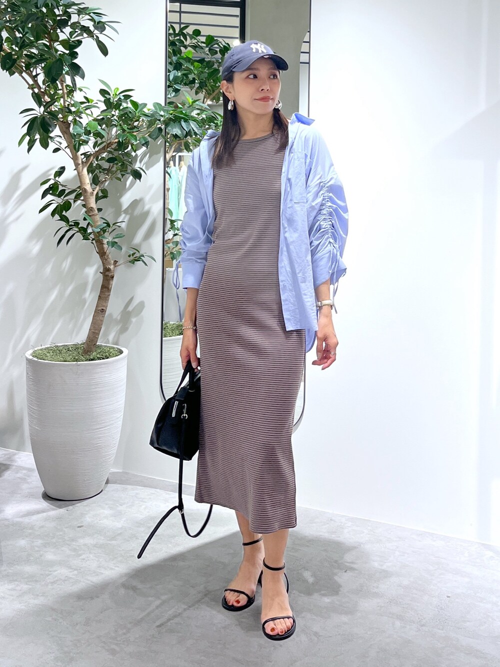 ブラウン系のワンピース、ブルー系のシャツ/ブラウス、ブラック系のショルダーバッグを着用したレディースの春コーディネートの2枚目の写真