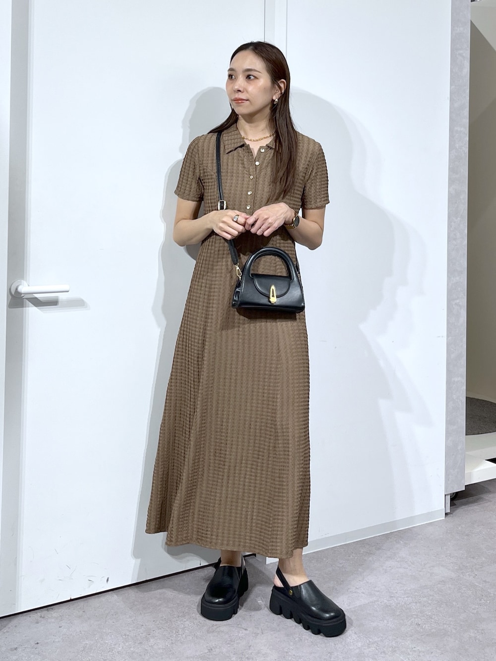 ブラック系のショルダーバッグ、ブラック系のサンダル、ブラウン系のワンピースを着用したレディースの春コーディネートの4枚目の写真