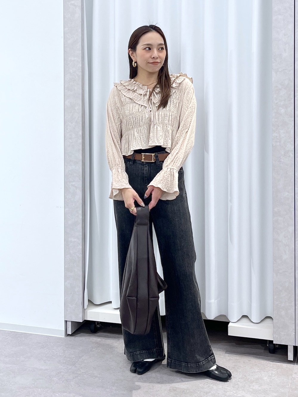 ベージュ系のシャツ/ブラウス、ブラウン系のトートバッグ、ブラック系のデニムパンツを着用したレディースの冬コーディネートの9枚目の写真