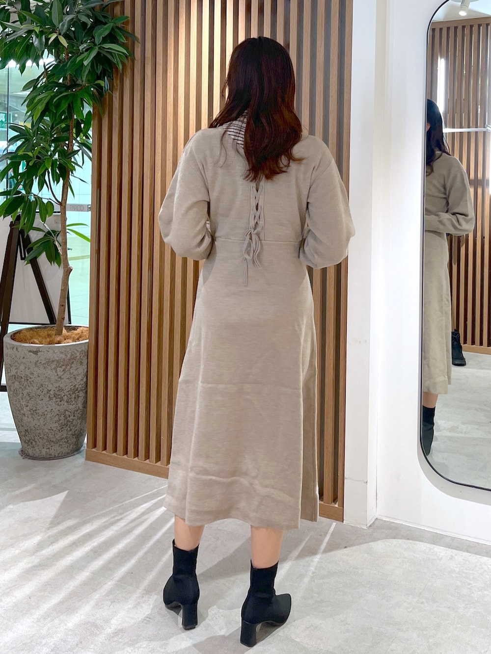 ブラック系のショルダーバッグ、ベージュ系のワンピース、ホワイト系のニット/セーターを着用したレディースの冬コーディネートの4枚目の写真