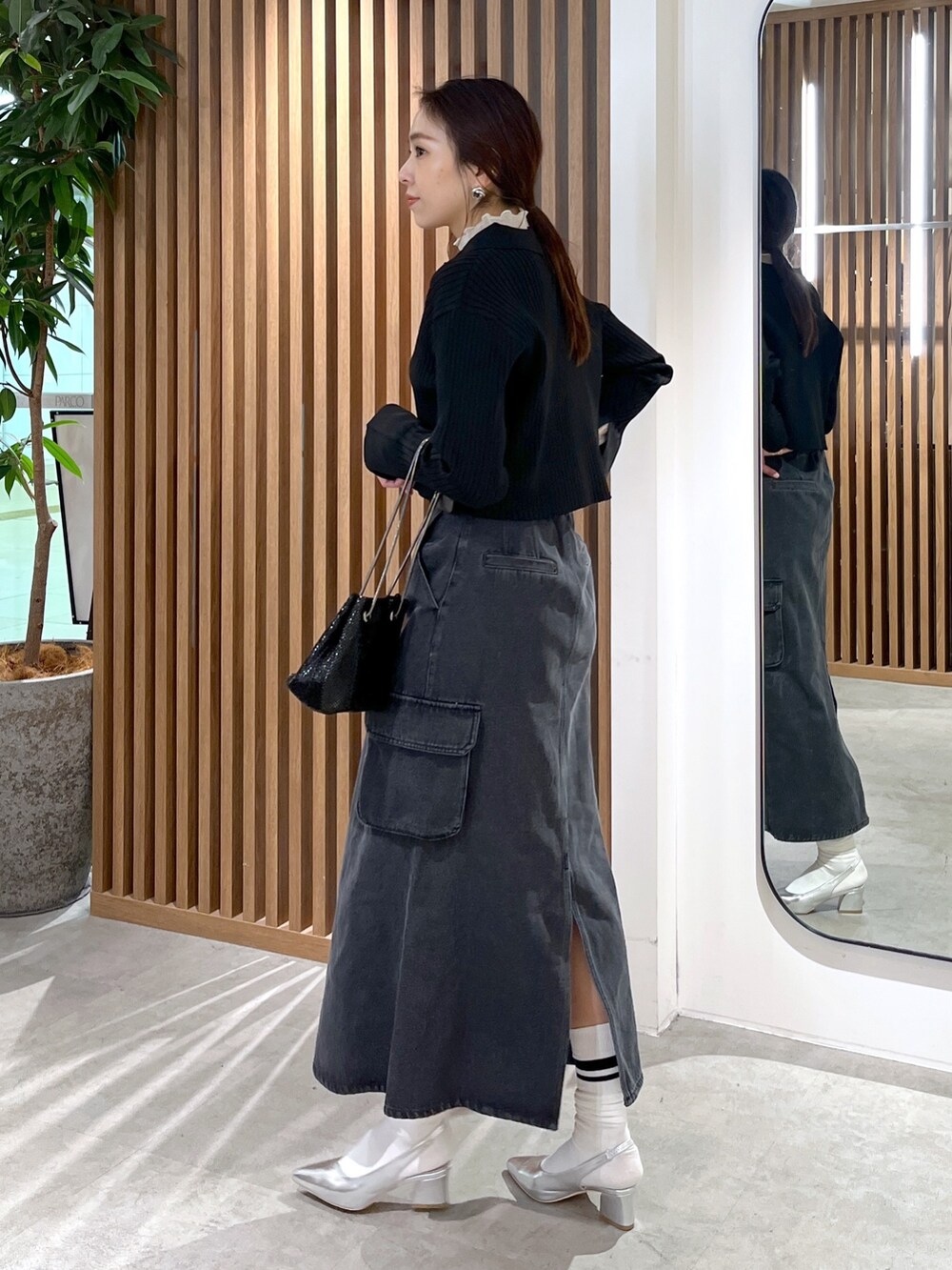 ブラック系のニット/セーター、ホワイト系のTシャツ/カットソー、ブラック系のショルダーバッグを着用したレディースの冬コーディネートの4枚目の写真