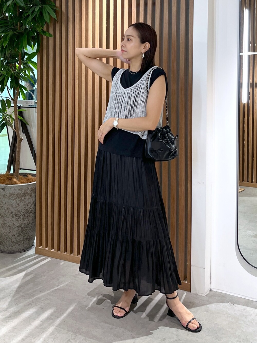 ブラック系のサンダル、ブラック系のスカート、ブラック系のショルダーバッグを着用したレディースの夏コーディネートの7枚目の写真