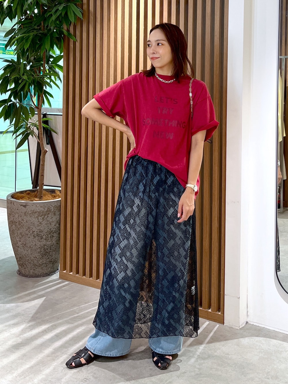 レッド系のTシャツ/カットソー、ブラック系のハンドバッグ、ブルー系のデニムパンツを着用したレディースの夏コーディネートの9枚目の写真