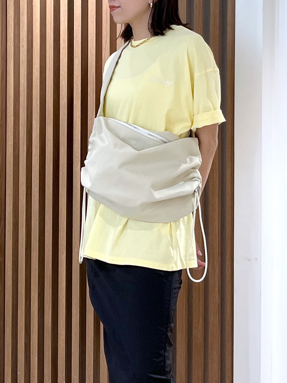 イエロー系のTシャツ/カットソー、ホワイト系のショルダーバッグ、ブラック系のスカートを着用したレディースの春コーディネートの8枚目の写真