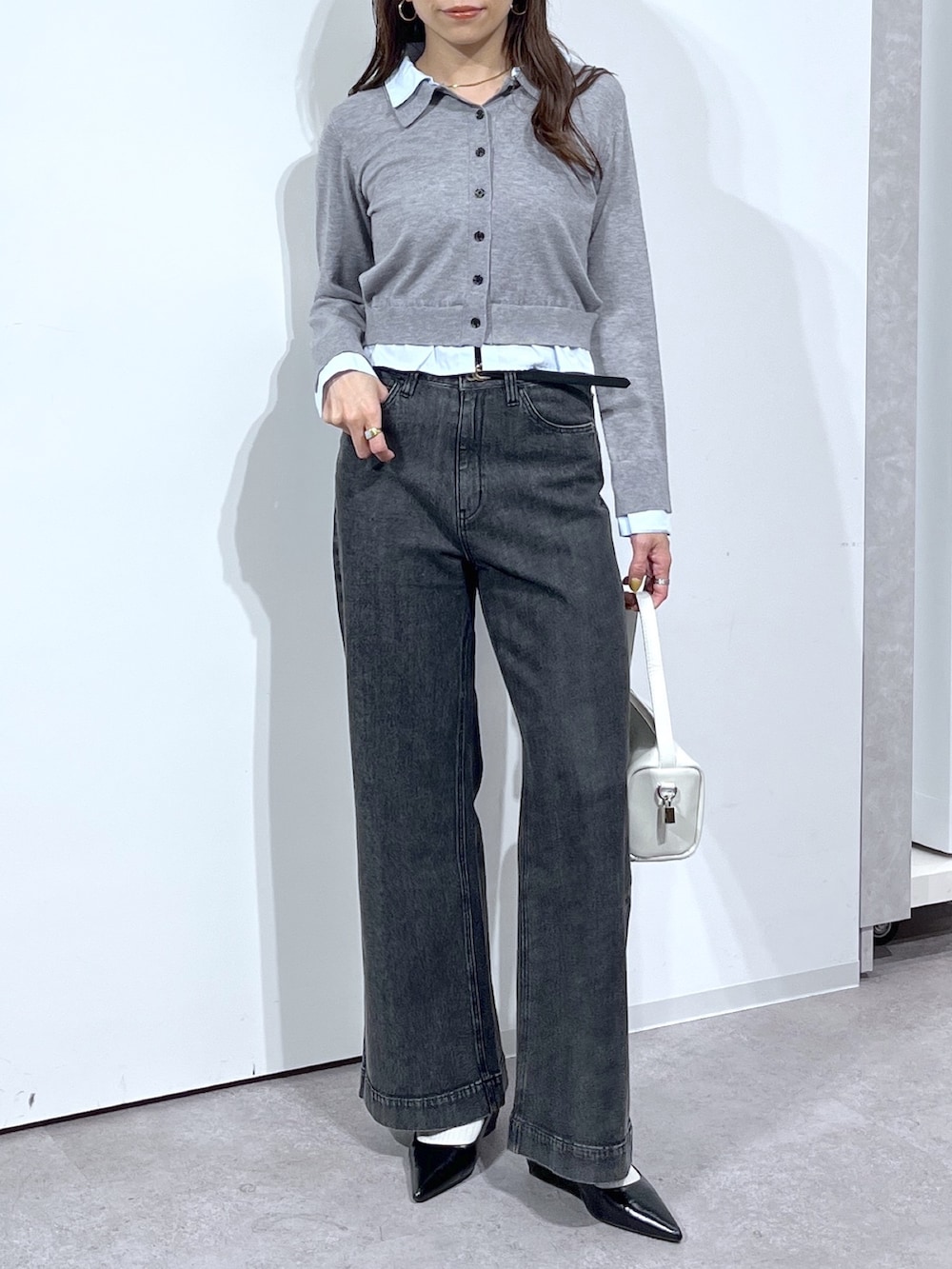 グレー系のニット/セーター、ホワイト系のハンドバッグ、ブラック系のデニムパンツを着用したレディースの春コーディネートの7枚目の写真