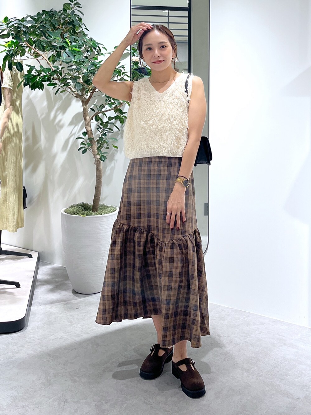 ブラウン系のシューズ、ブラック系のショルダーバッグ、ホワイト系のニット/セーターを着用したレディースの夏コーディネートの2枚目の写真