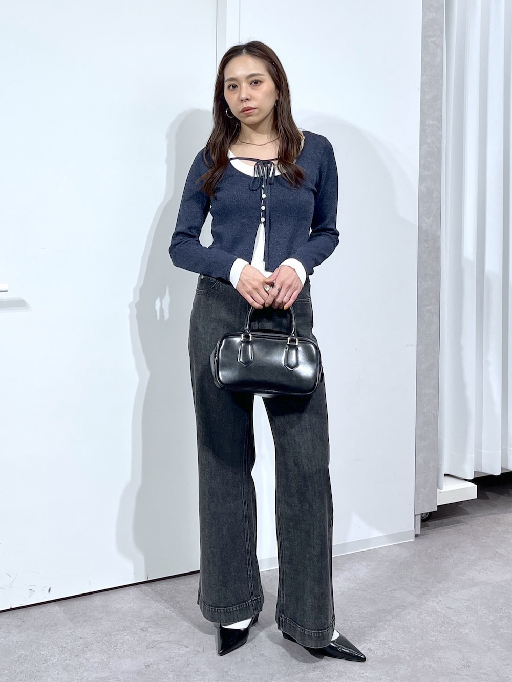 ブラック系のハンドバッグ、ブラック系のパンプス、ブラック系のデニムパンツを着用したレディースの春コーディネートの3枚目の写真