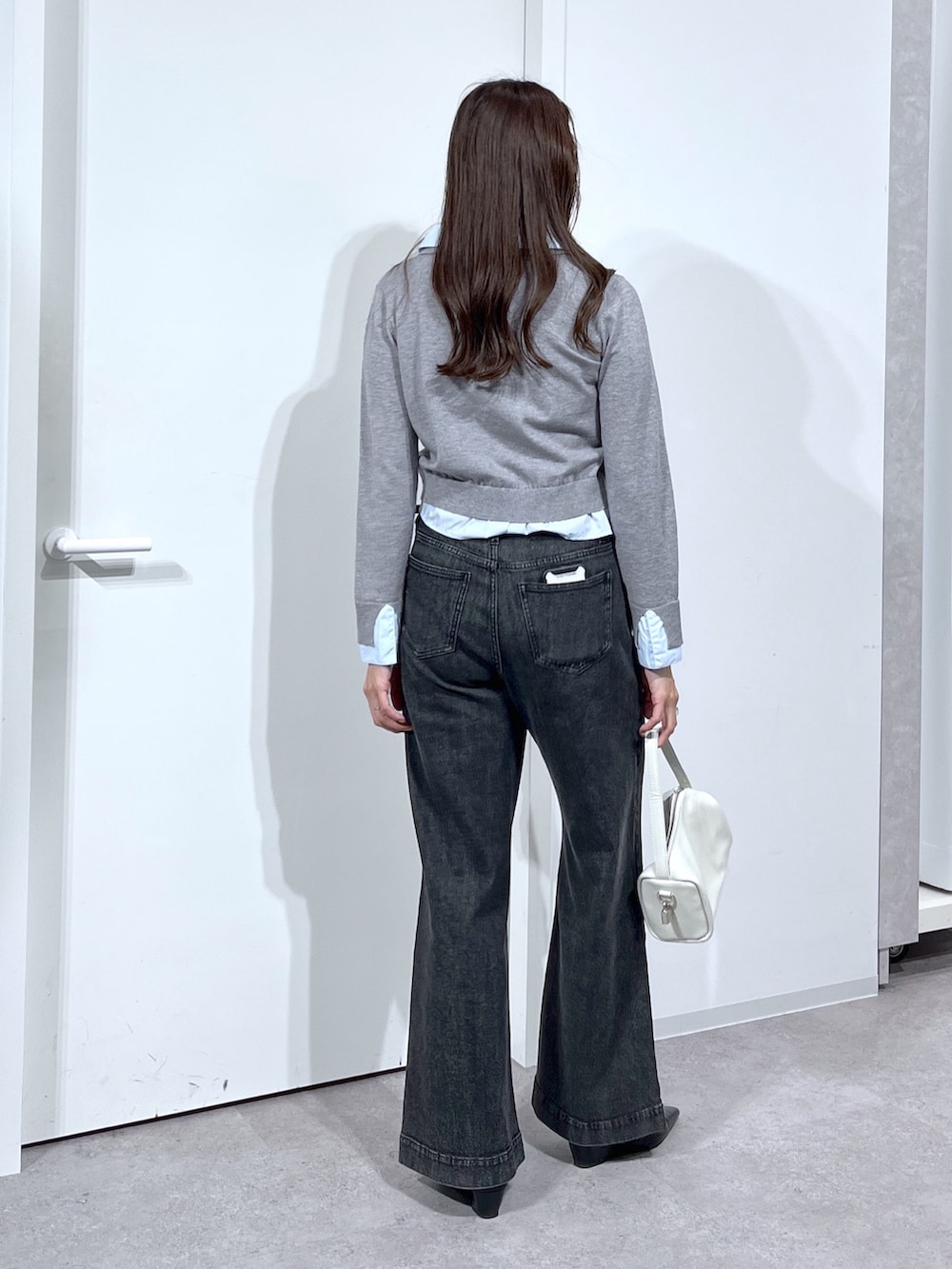 グレー系のニット/セーター、ホワイト系のハンドバッグ、ブラック系のデニムパンツを着用したレディースの春コーディネートの9枚目の写真