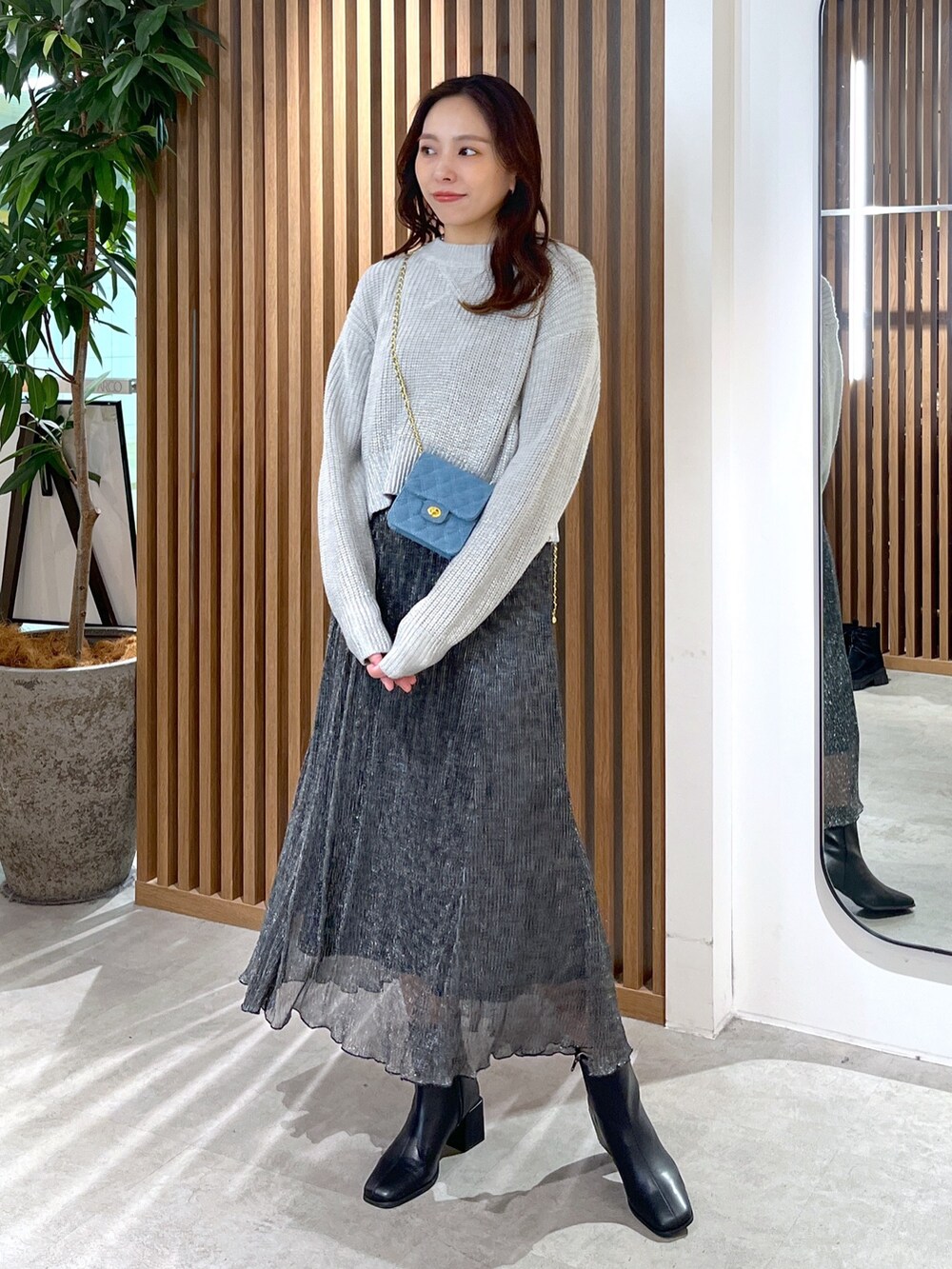 グレー系のニット/セーター、ブルー系のショルダーバッグ、ブラック系のスカートを着用したレディースの冬コーディネートの2枚目の写真