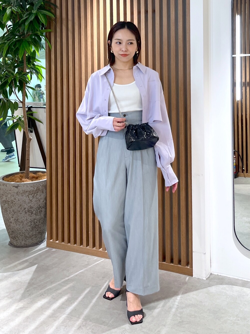 ブラック系のサンダル、グレー系のスラックス、ブラック系のショルダーバッグを着用したレディースの春コーディネートの4枚目の写真