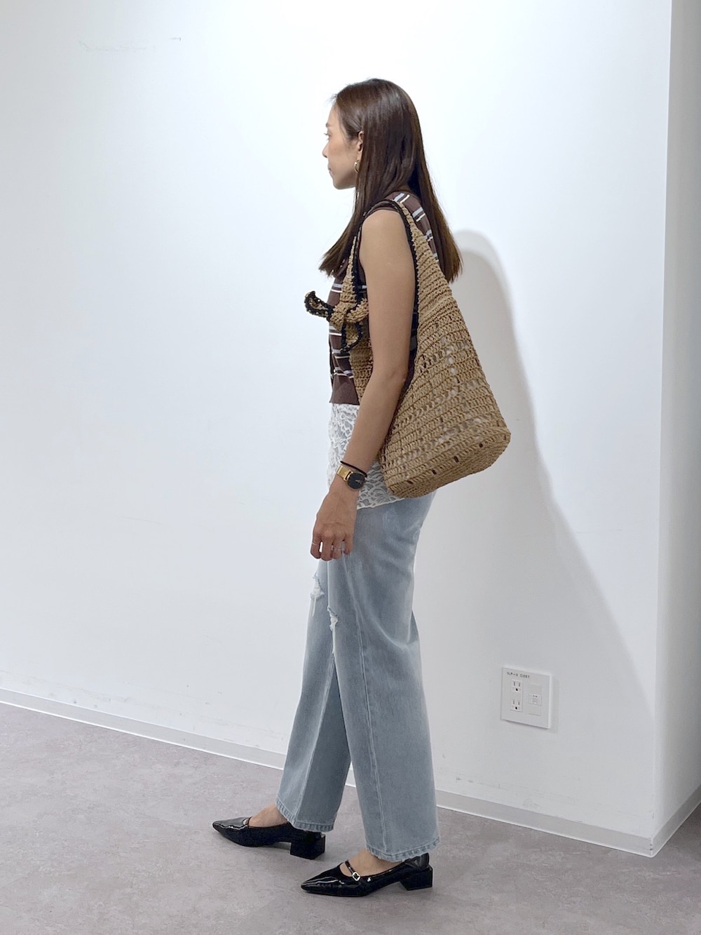 ブラウン系のニット/セーター、ブラック系のパンプス、ブルー系のデニムパンツを着用したレディースの夏コーディネートの4枚目の写真