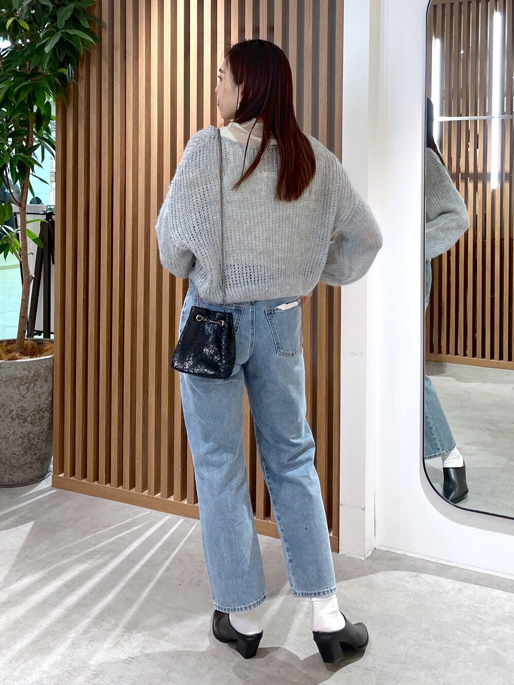 グレー系のニット/セーター、ホワイト系のTシャツ/カットソー、ブルー系のデニムパンツを着用したレディースの冬コーディネートの5枚目の写真