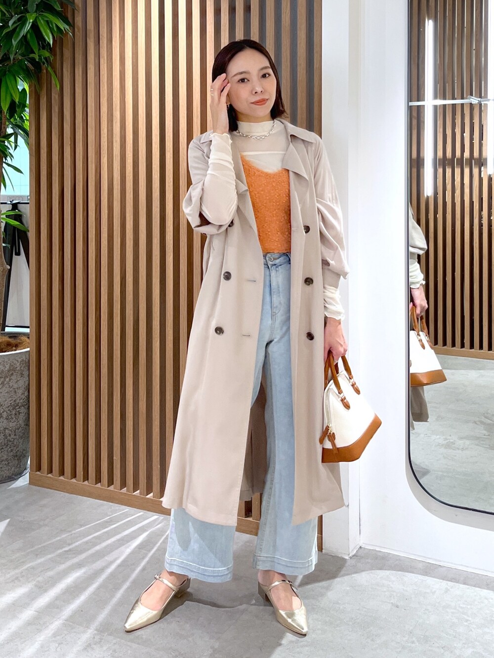 ブラウン系のショルダーバッグ、ホワイト系のTシャツ/カットソー、オレンジ系のベストを着用したレディースの春コーディネートの3枚目の写真