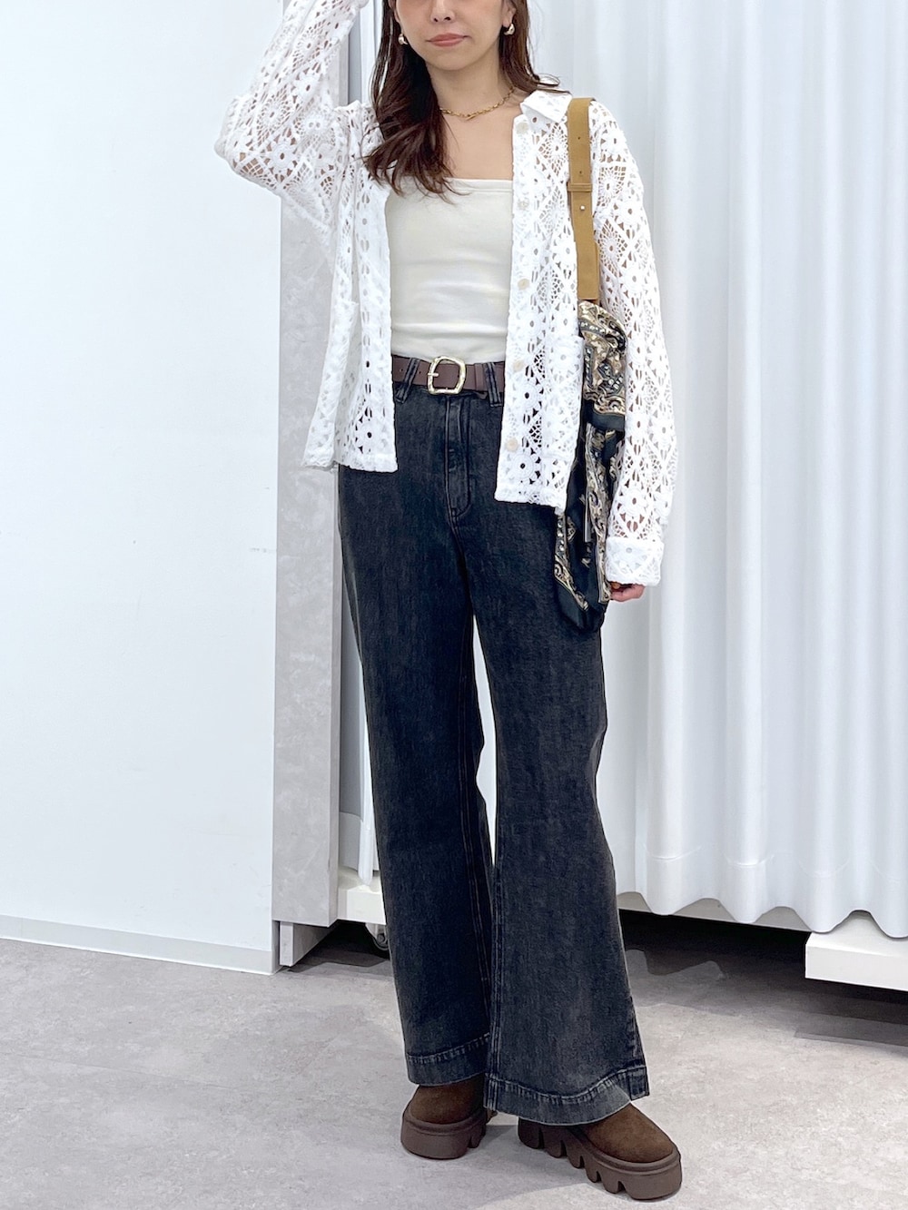 ホワイト系のブルゾン、ブラウン系のショルダーバッグ、ブラック系のデニムパンツを着用したレディースの春コーディネートの5枚目の写真