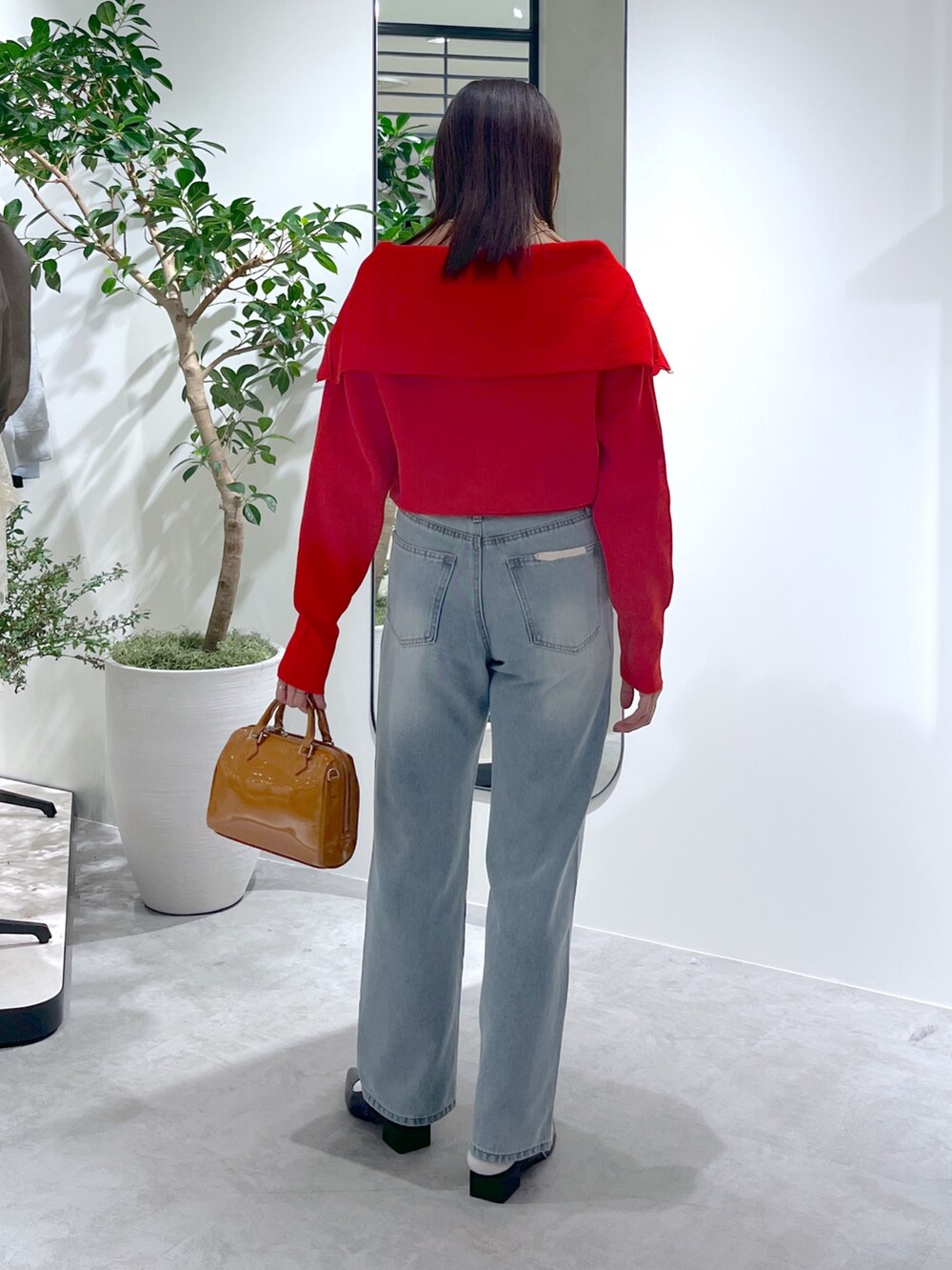 レッド系のニット/セーター、ブルー系のデニムパンツ、ベージュ系のショルダーバッグを着用したレディースの春コーディネートの8枚目の写真