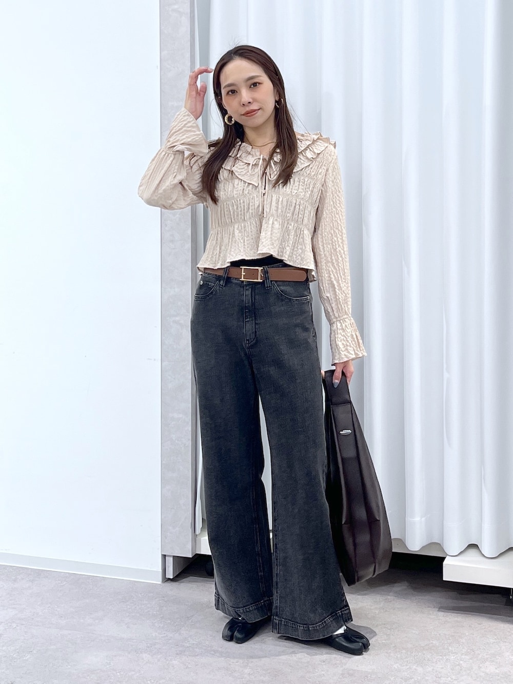 ベージュ系のシャツ/ブラウス、ブラウン系のトートバッグ、ブラック系のデニムパンツを着用したレディースの冬コーディネートの3枚目の写真