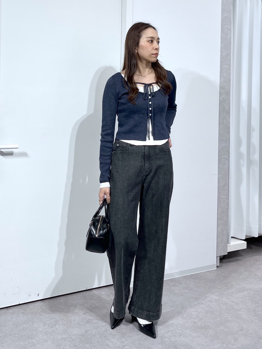 ブラック系のハンドバッグ、ブラック系のパンプス、ブラック系のデニムパンツを着用したレディースの春コーディネートの9枚目の写真