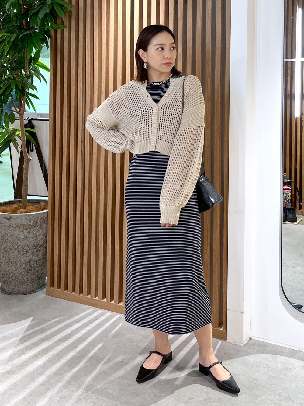 ベージュ系のカーディガン/ボレロ、ブラック系のショルダーバッグ、ブラック系のワンピースを着用したレディースの春コーディネートの6枚目の写真