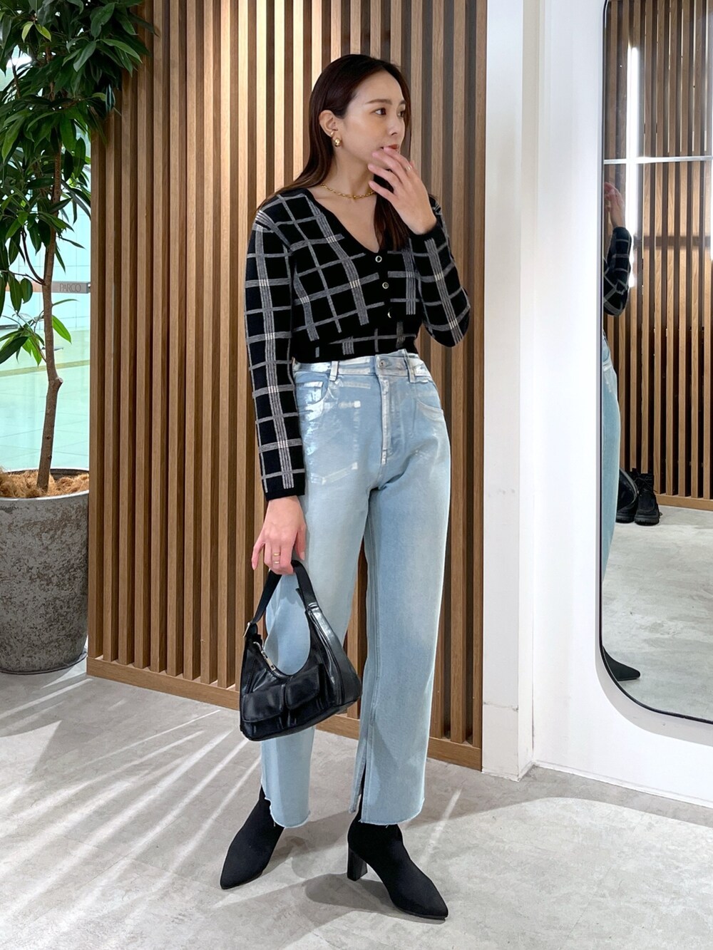 ブルー系のデニムパンツ、ブラック系のニット/セーター、ブラック系のショルダーバッグを着用したレディースの冬コーディネートの3枚目の写真