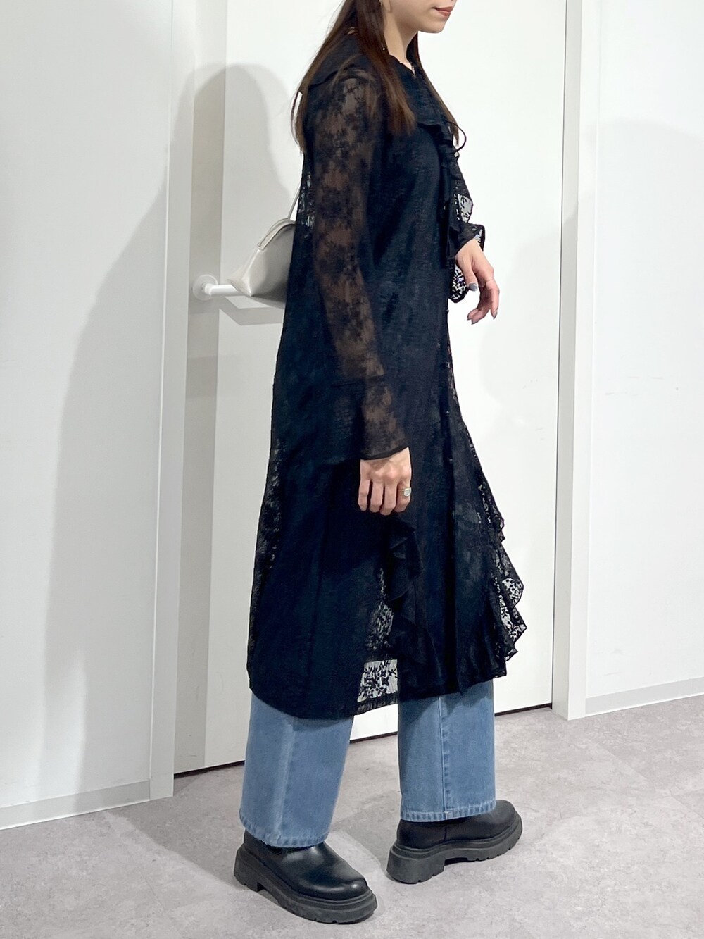 ホワイト系のショルダーバッグ、ブラック系のワンピース、ブルー系のデニムパンツを着用したレディースの冬コーディネートの6枚目の写真