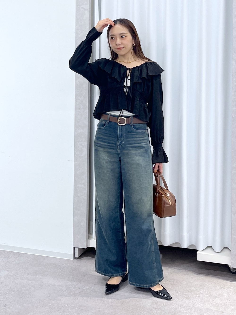 ブラック系のシャツ/ブラウス、ブルー系のデニムパンツ、ブラウン系のハンドバッグを着用したレディースの春コーディネートの3枚目の写真