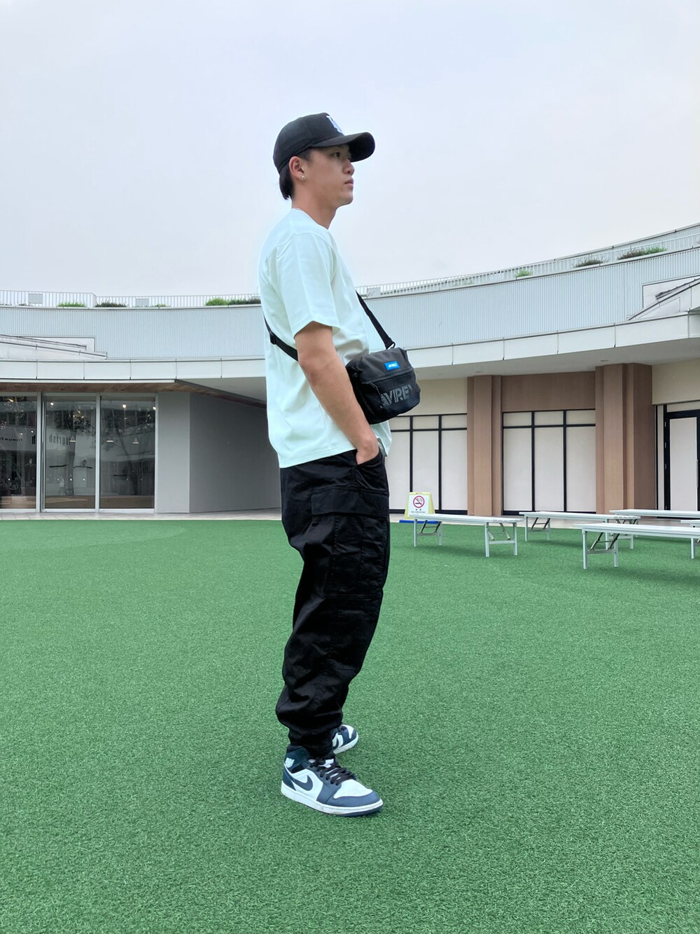 ホワイト系のTシャツ/カットソー、ブラック系のショルダーバッグ、ブラック系のカーゴパンツを着用したメンズの夏コーディネートの2枚目の写真