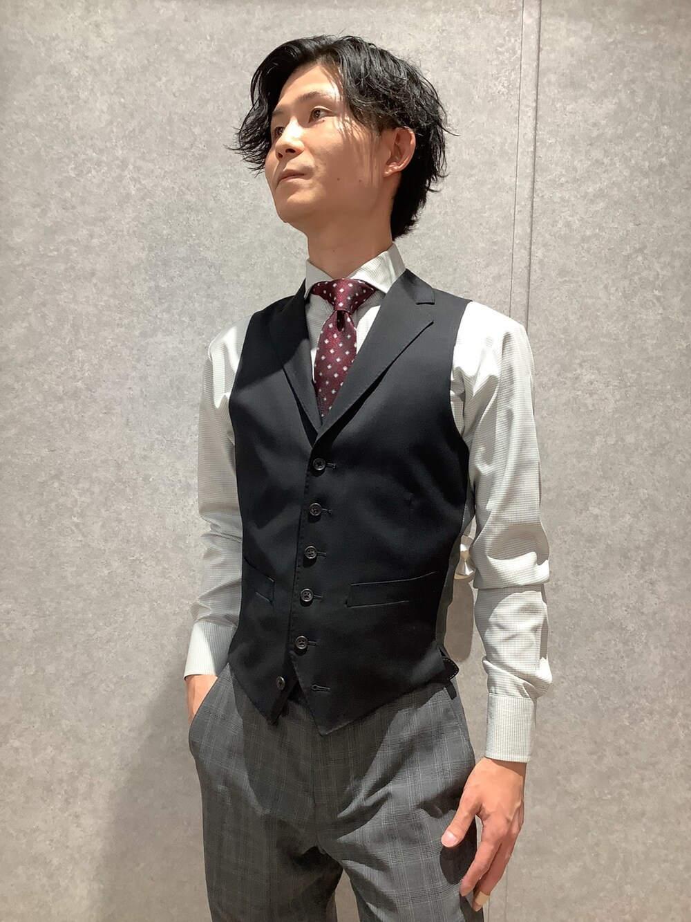 グレー系のビジネスシャツ、レッド系のネクタイを着用したメンズの冬コーディネートの2枚目の写真