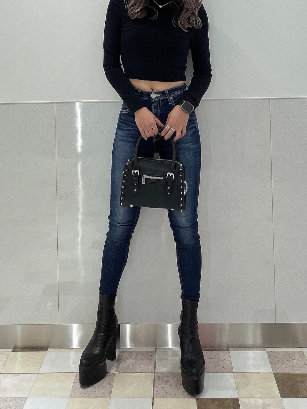 ブルー系のデニムパンツ、ブラック系のブーツ、ブラック系のボストンバッグを着用したレディースの秋コーディネートの3枚目の写真