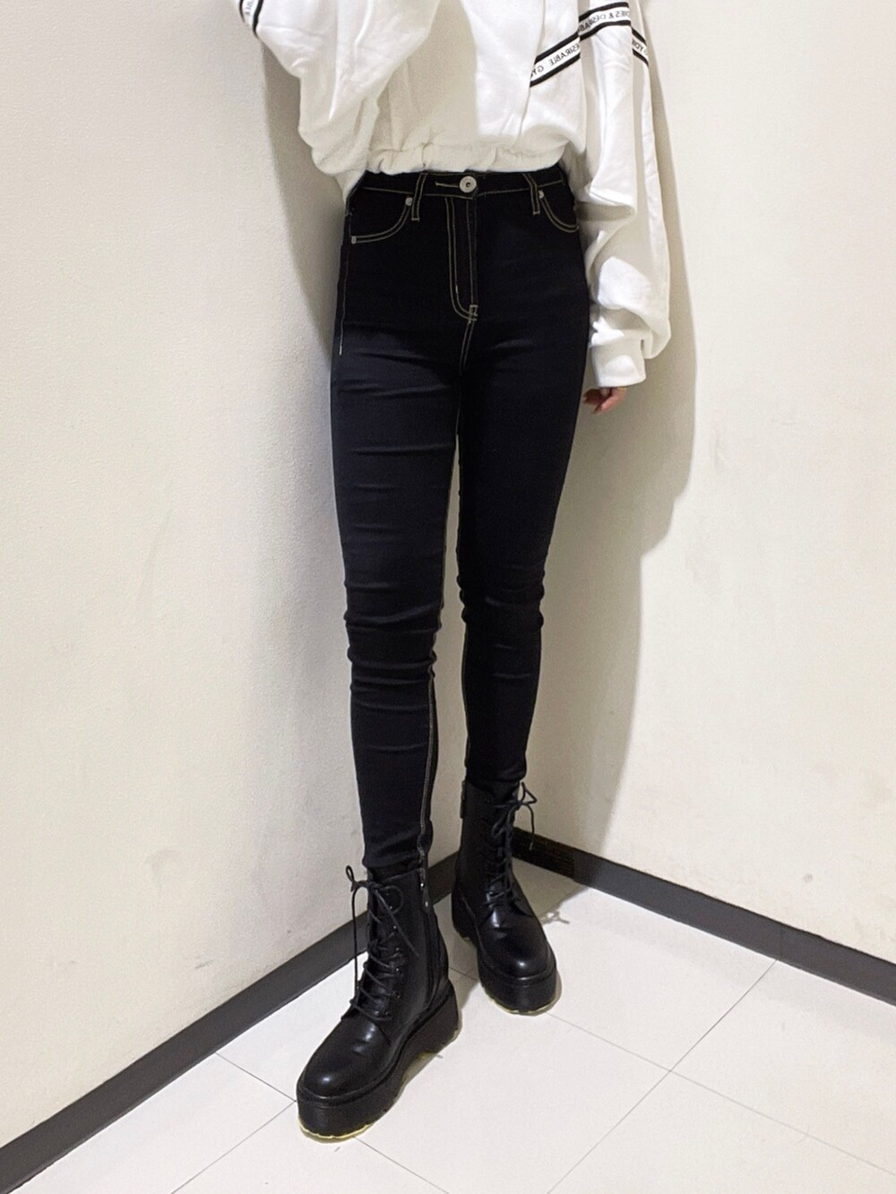 ホワイト系のスウェット、ブラック系のデニムパンツ、ブラック系のブーツを着用したレディースの秋コーディネートの6枚目の写真