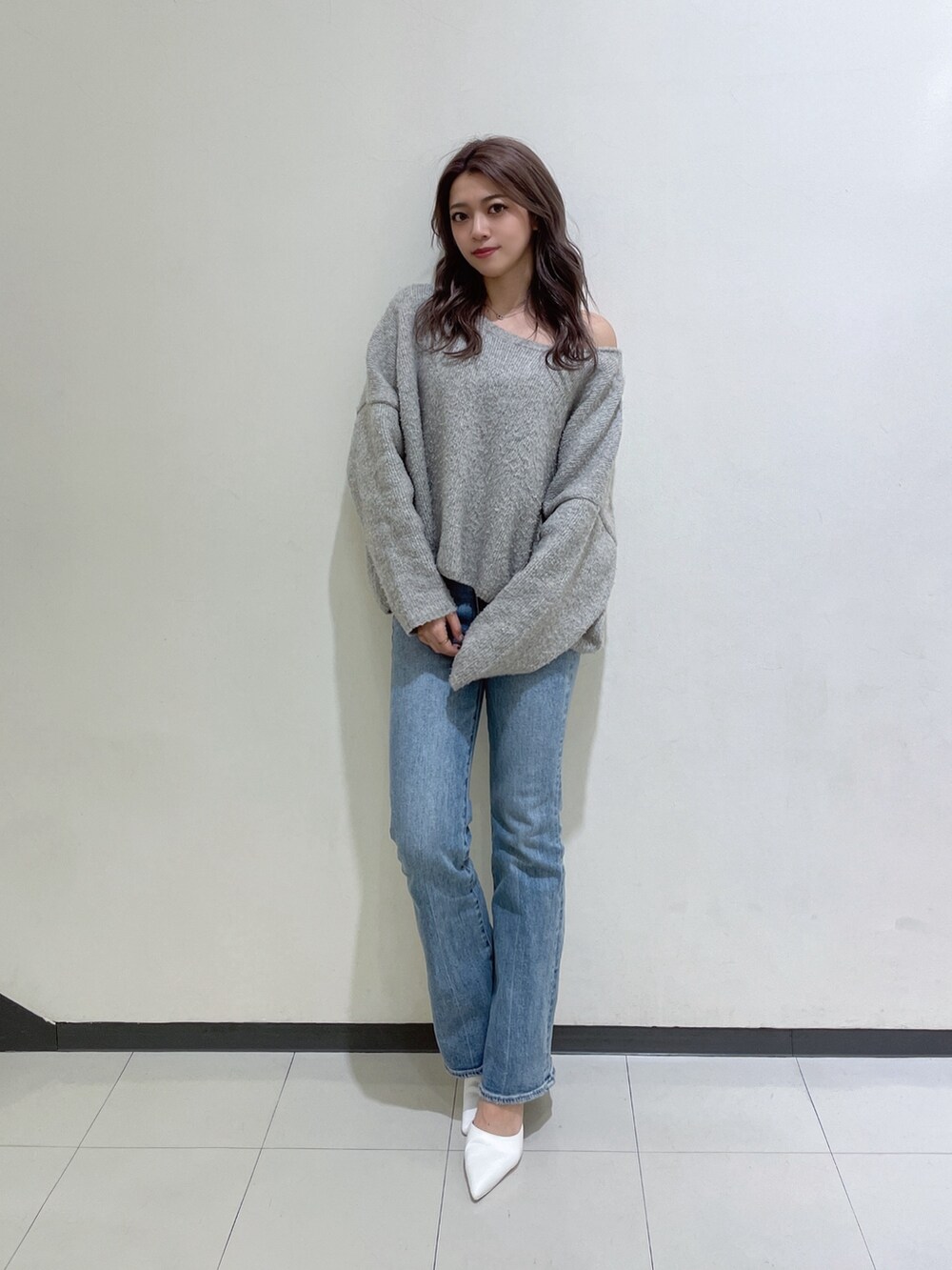 グレー系のニット/セーター、ブルー系のデニムパンツ、ホワイト系のパンプスを着用したレディースの冬コーディネートの2枚目の写真