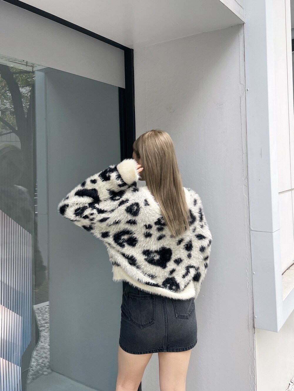 ホワイト系のニット/セーター、ブラック系のデニムスカート、ブラック系のブーツを着用したレディースの冬コーディネートの4枚目の写真