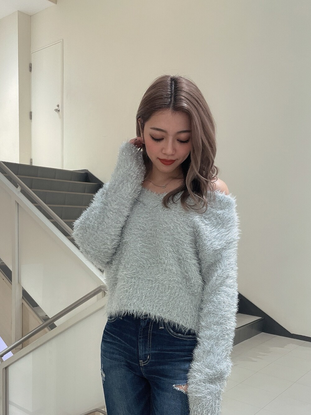 グレー系のニット/セーター、ブルー系のデニムパンツ、ホワイト系のパンプスを着用したレディースの冬コーディネートの5枚目の写真