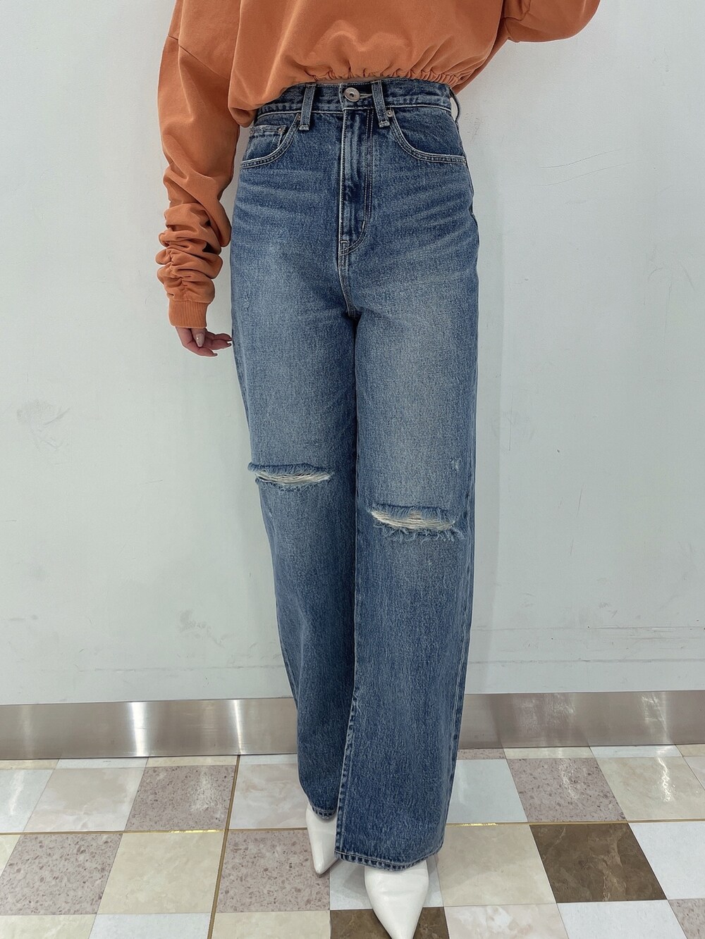 オレンジ系のTシャツ/カットソー、ブルー系のデニムパンツ、ホワイト系のパンプスを着用したレディースの冬コーディネートの6枚目の写真