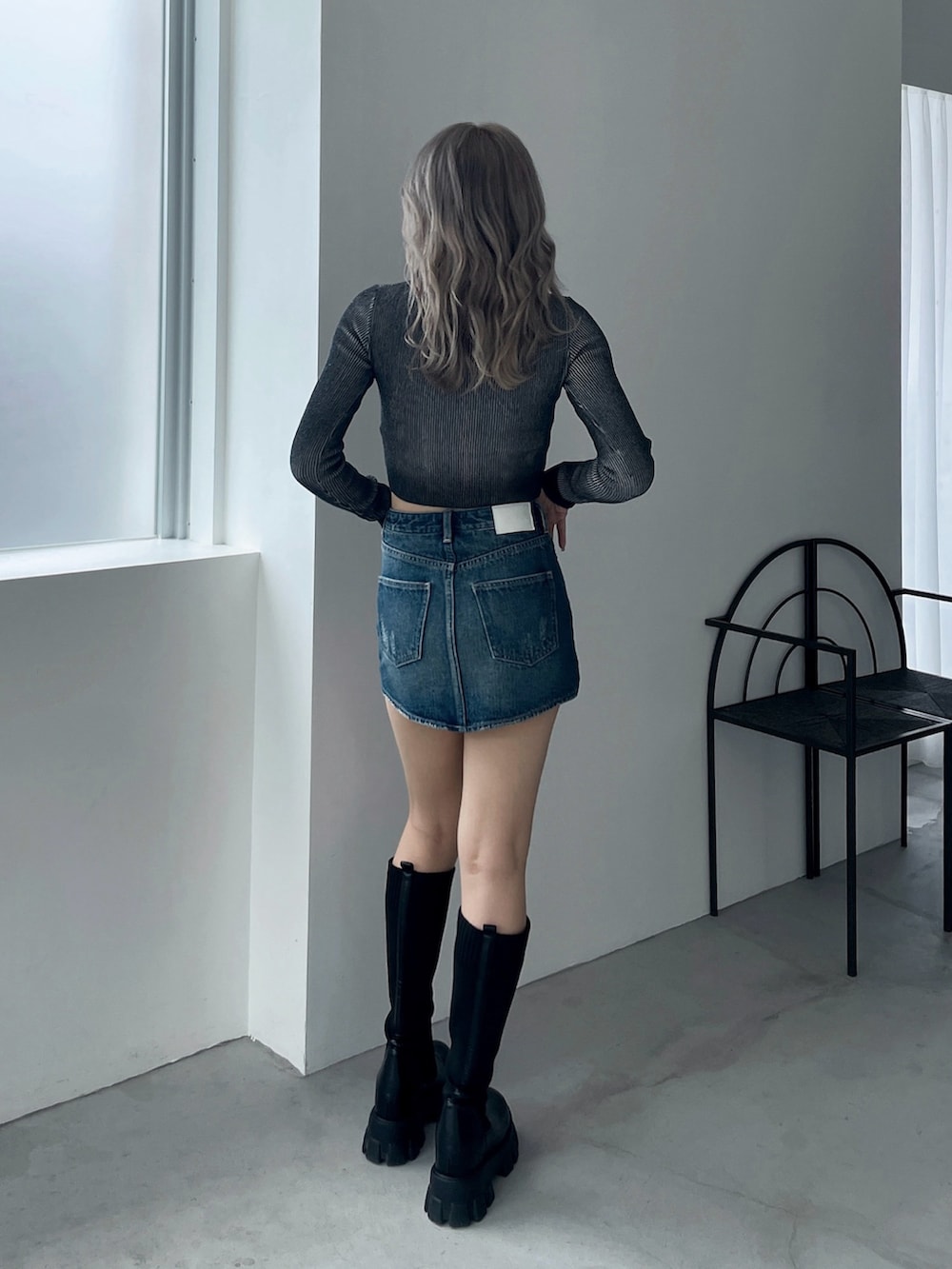 ブラック系のニット/セーター、ブルー系のデニムスカート、ブラック系のブーツを着用したレディースの秋コーディネートの3枚目の写真