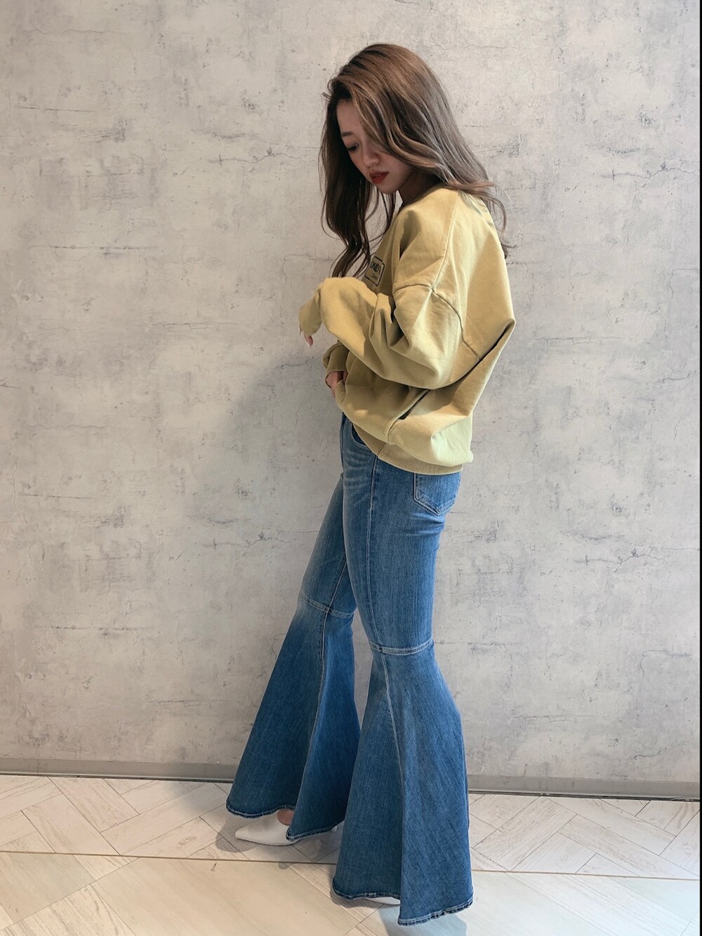 ホワイト系のパンプス、ブルー系のデニムパンツ、イエロー系のスウェットを着用したレディースの冬コーディネートの2枚目の写真