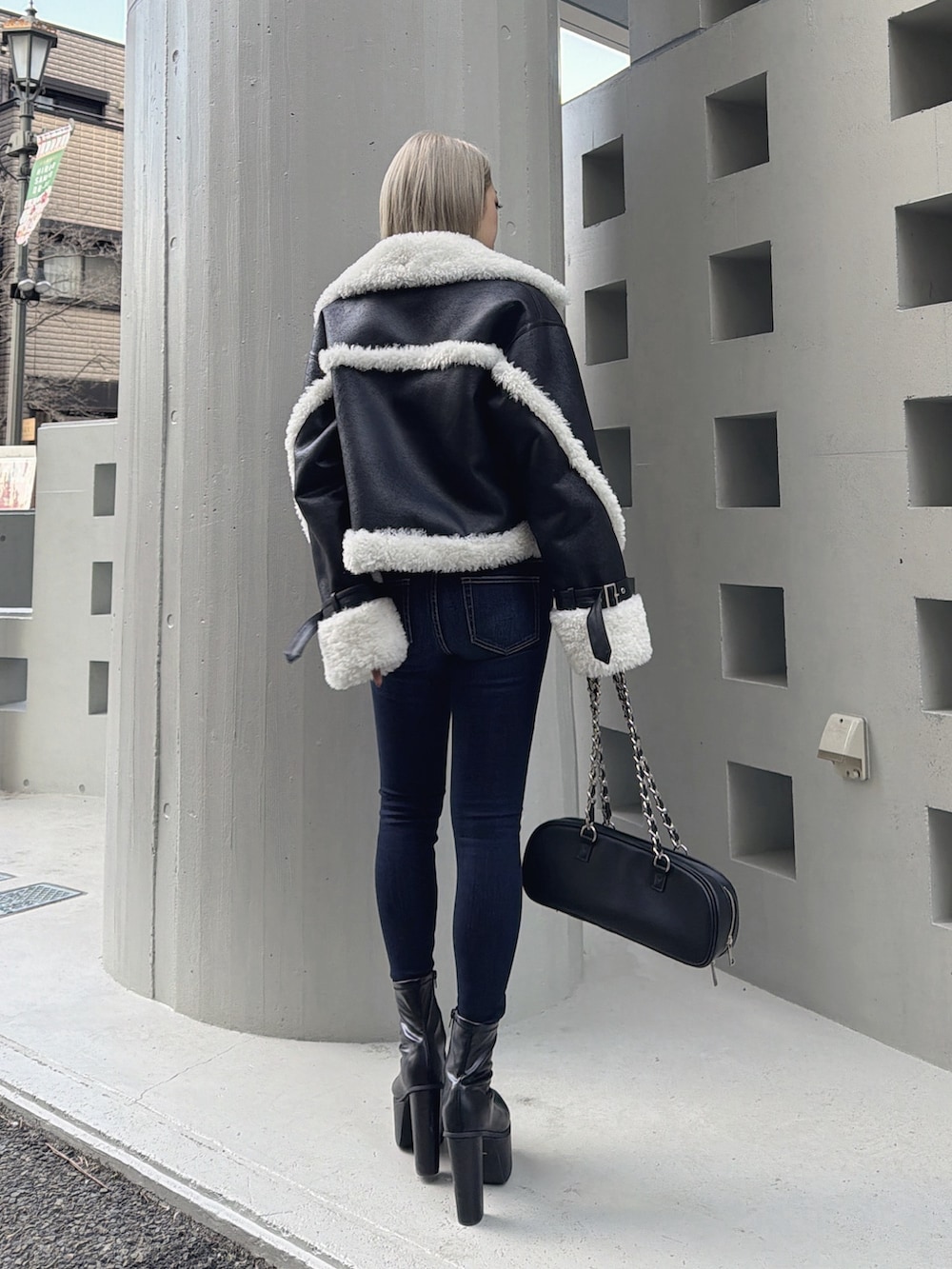 ブラック系のムートンコート、ホワイト系のTシャツ/カットソー、ブルー系のデニムパンツを着用したレディースの冬コーディネートの2枚目の写真