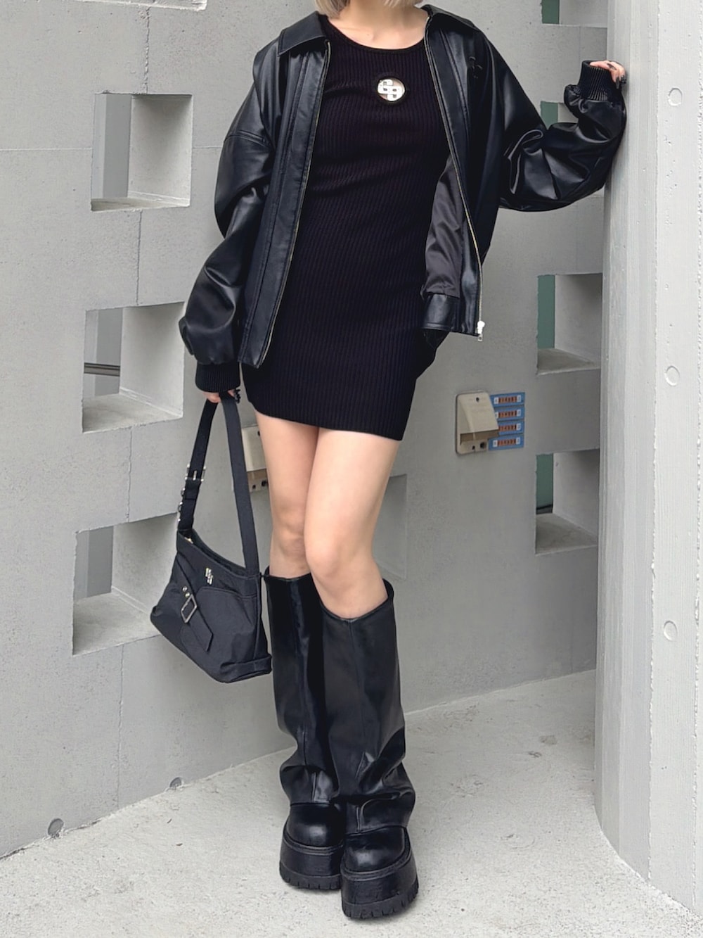 ブラック系のブルゾン、ブラック系のワンピース、ブラック系のブーツを着用したレディースの春コーディネートの3枚目の写真