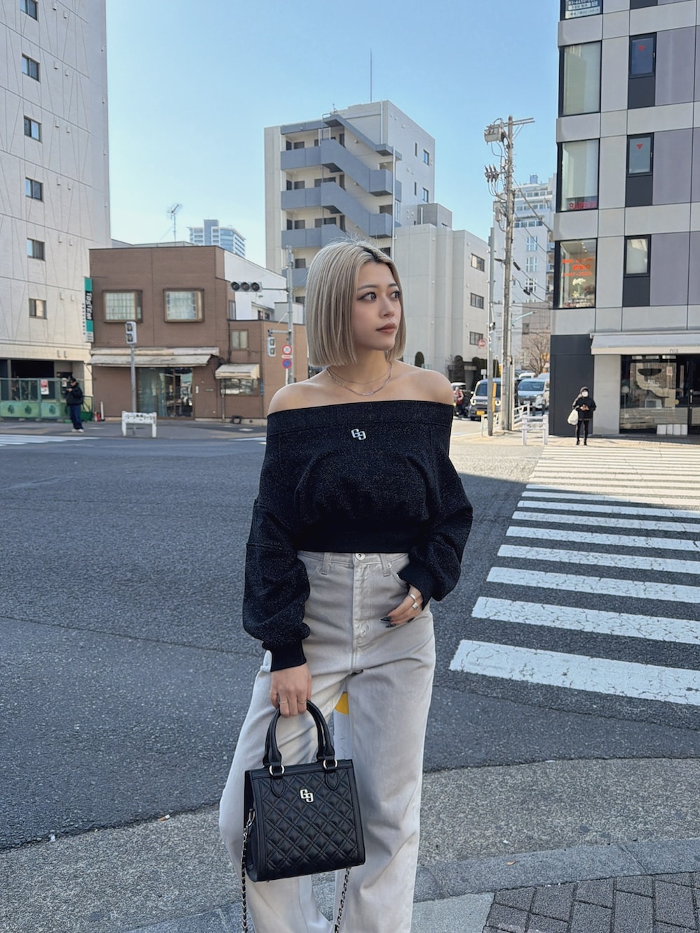 ブラック系のTシャツ/カットソー、ホワイト系のデニムパンツ、ブラック系のショルダーバッグを着用したレディースの冬コーディネートの4枚目の写真