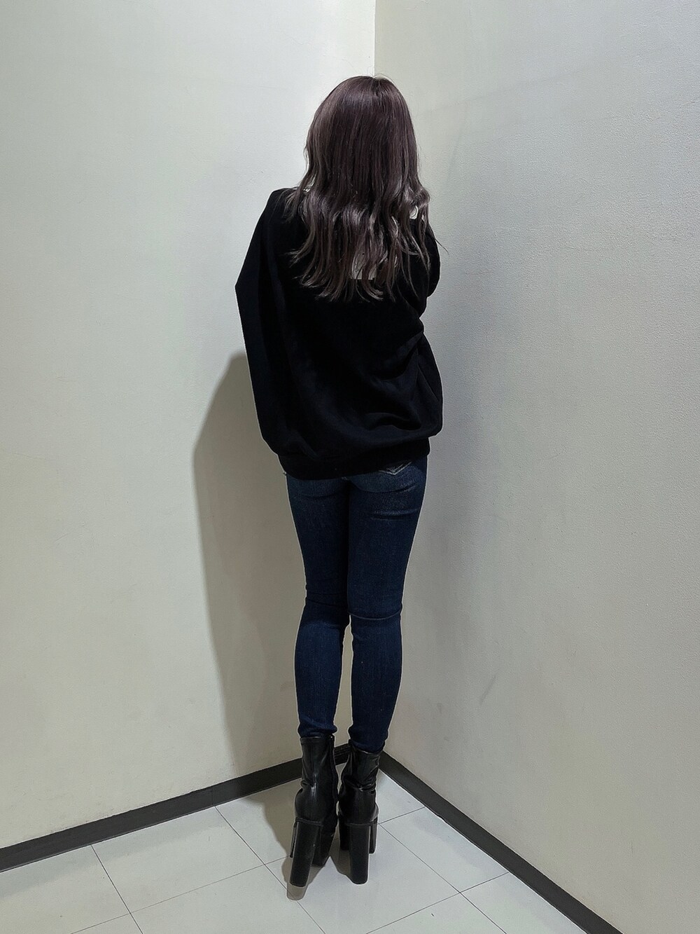 ブラック系のスウェット、ブルー系のデニムパンツ、ブラック系のブーツを着用したレディースの秋コーディネートの2枚目の写真